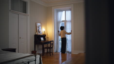 calm girl looking window in bedroom back view. african lady moving body dancing