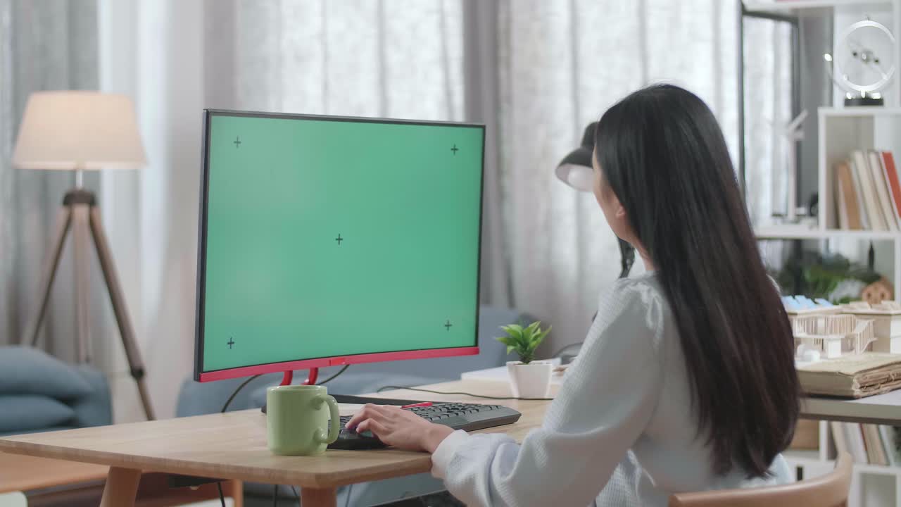 집 모델과 함께 아시아 여성 엔지니어가 집에서 모의 녹색 화면 데스크에서 일하고 있습니다.