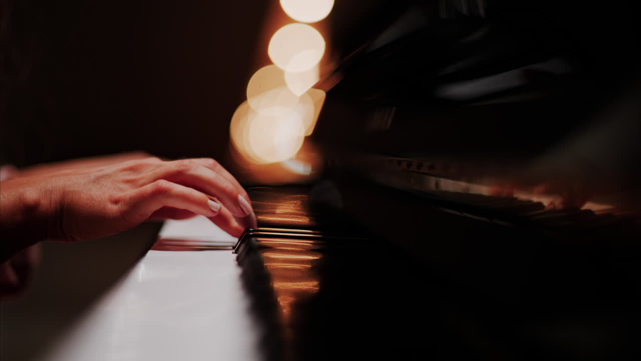 Close up of a woman's hands playing the piano with blurry lights on the background