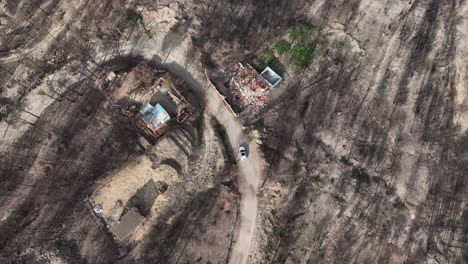 car driving past house remains in burnt forest of el pont de vilomara in spain - aerial top down