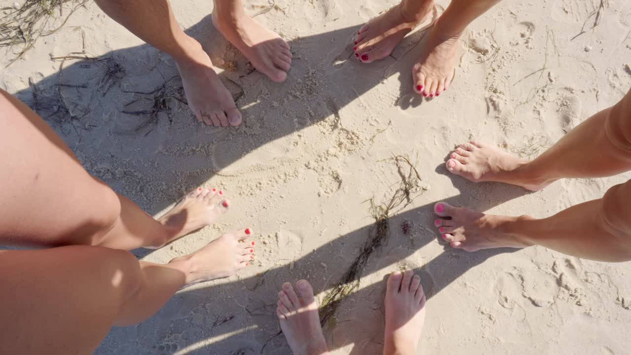 las piernas de diferentes personas en la arena mientras se relajan. amigos se pararon en círculo. concepto de vacaciones conjuntas.