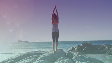 animación de luces brillantes sobre una mujer biracial practicando yoga junto al mar