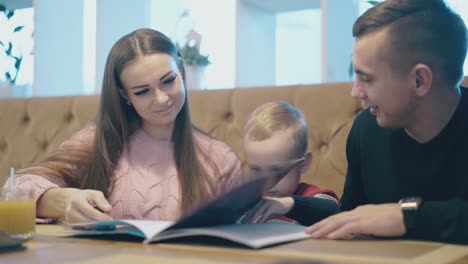 un niño pequeño se sienta entre una señora bonita y un hombre guapo