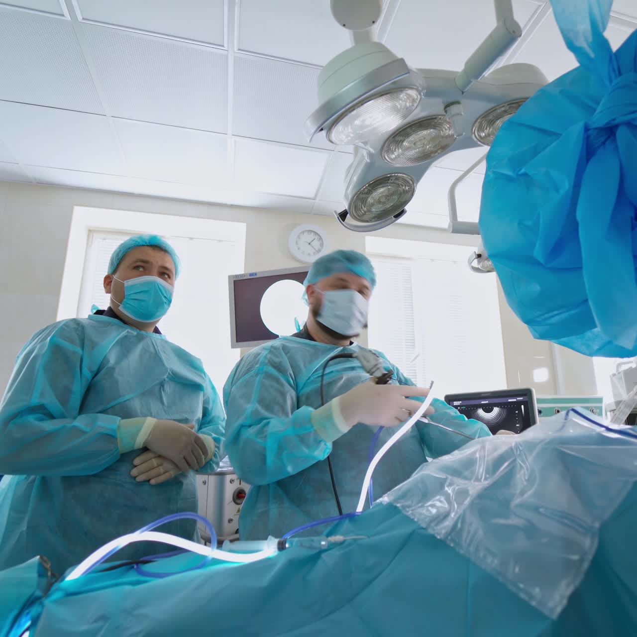 Professional surgeons during the operation to a patient. Doctors in medical uniform conducting a surgery on a patient in the modern hospital.