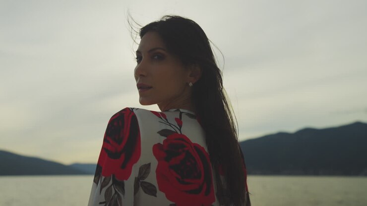 Donna in abito floreale al lago al tramonto