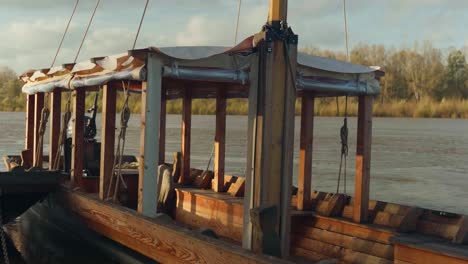 river water flowing in the background, cockpit of wooden vessel sits empty