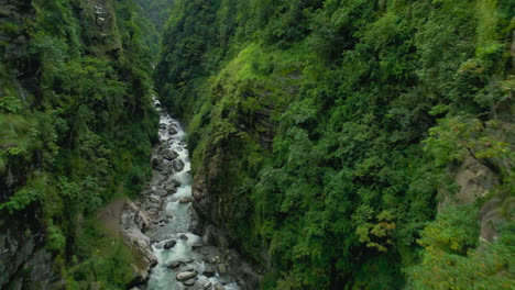 Drone-travels-between-two-cliffs-of-green-hills,-river-flowing,-shot-like-FPV,-Trees,-landscape-of-Nepal,-cinematic-4K