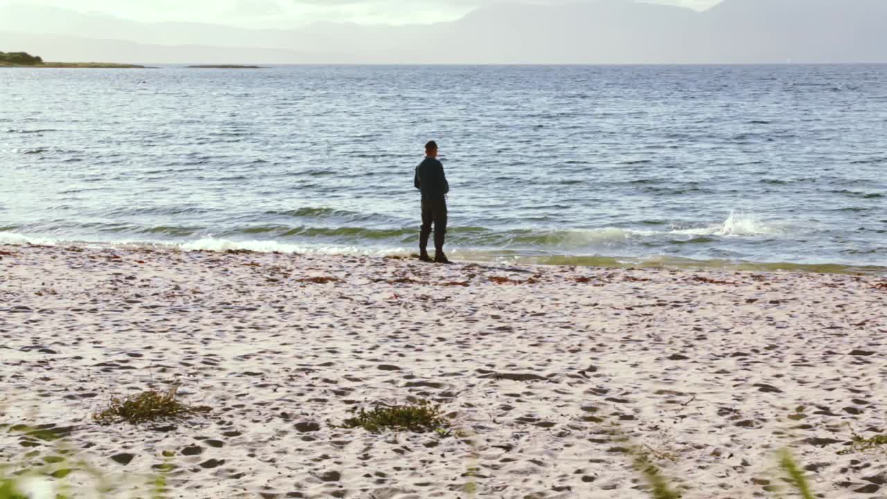 el hombre juega a buscar con su perro golden retriever en ocean beach durante una tarde soleada