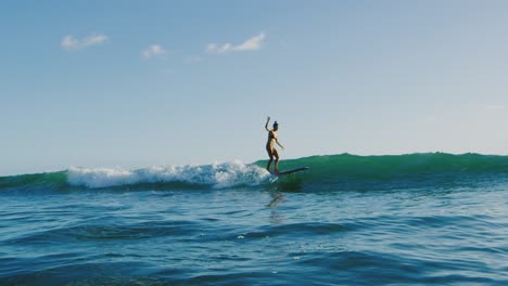 una mujer joven surfeando al atardecer.
