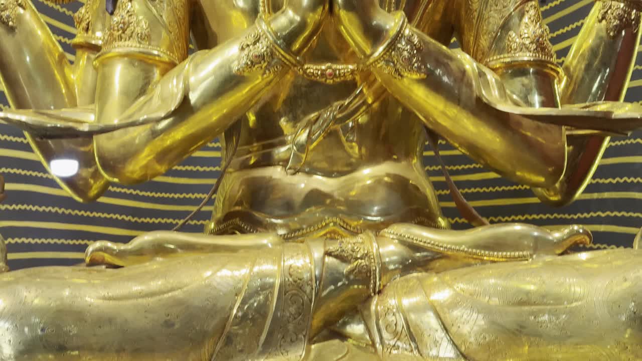 僧院の内部に雄大に立つ巨大な仏像。穏やかな表情と精緻な細部が、神聖な屋内の雰囲気の中で表現されている。