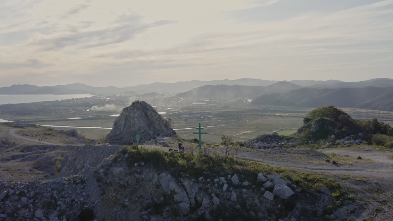 절단된 정상으로 산 위를 날고 먼 산등성이를 드러내고, 일몰 시간 동안 만에 정박한 도시와 배, 공중 사격