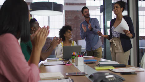 happy mixed race business colleagues sitting having a discussion in meeting room clapping