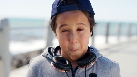 cara cómica, juguetona y niño por el mar