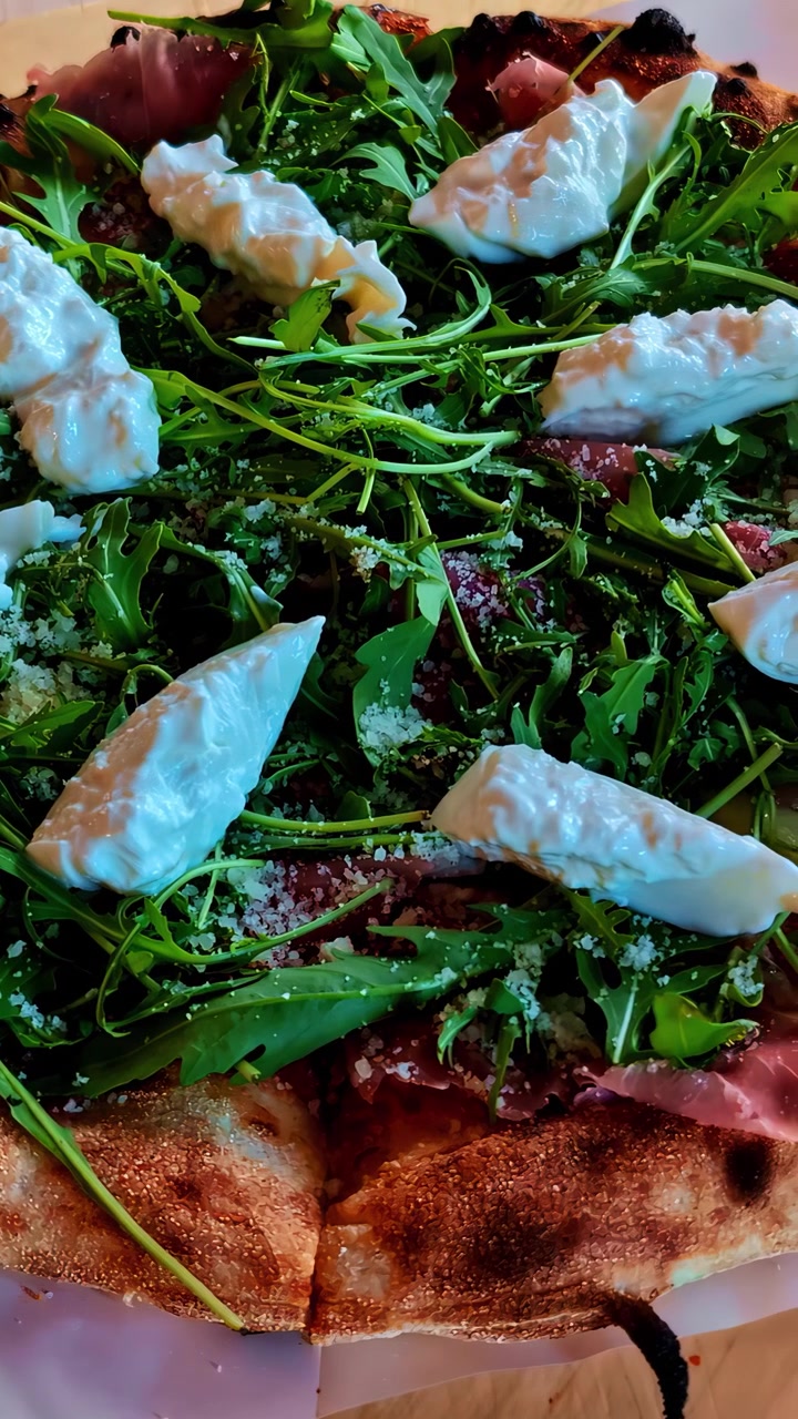 Un primo piano di una pizza gourmet guarnita con rucola e ricotta