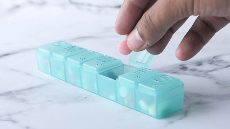 Hand opening a daily pill organizer