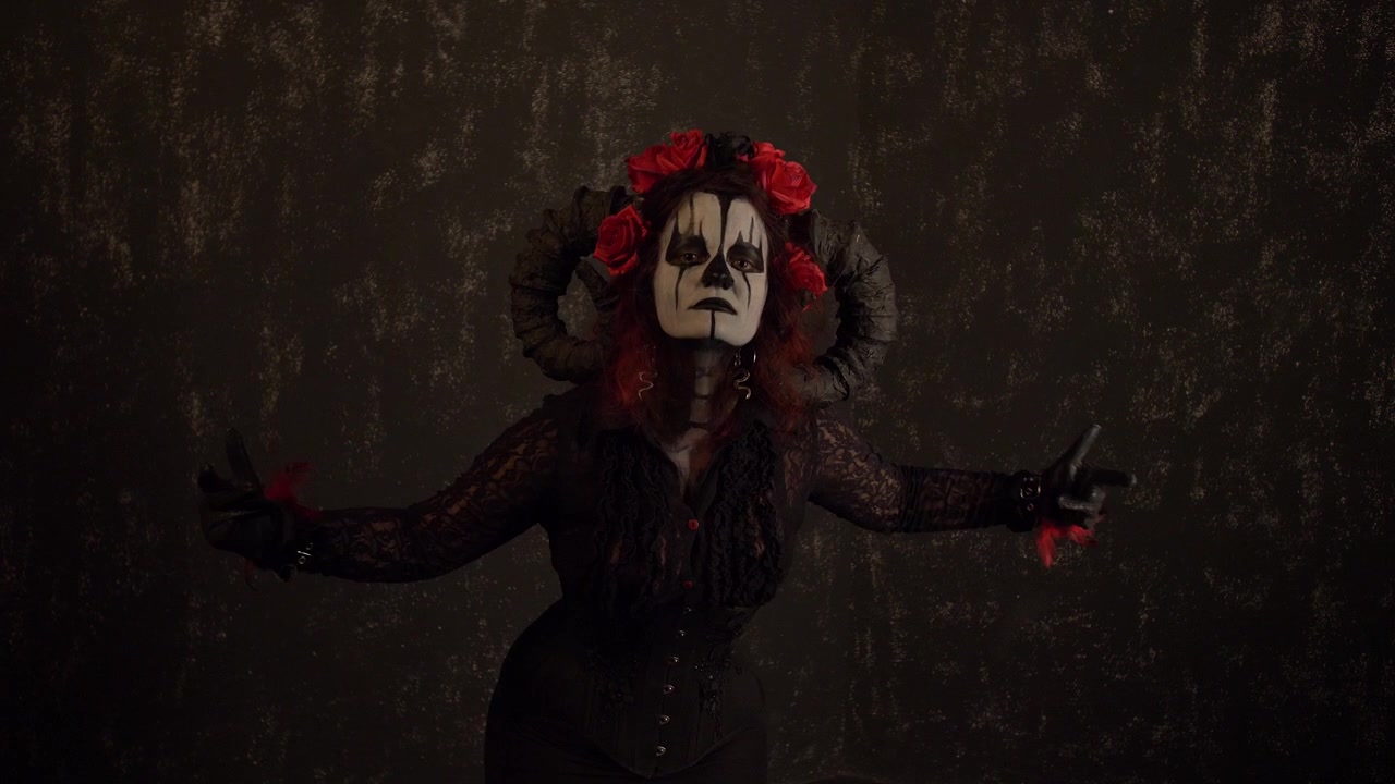 Catrina Cosplay meisje dat uitnodigend reikt met haar handen, gekleed in een opvallende, krachtige outfit, tegen een donkere achtergrond, medium close-up