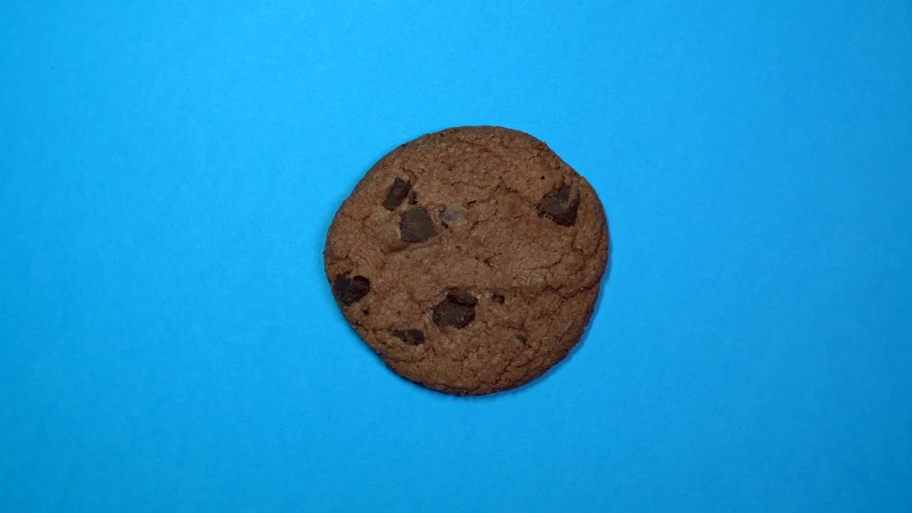 una galleta de chocolate en primer plano, una foto macro, girando rápidamente sobre un fondo azul giratorio.