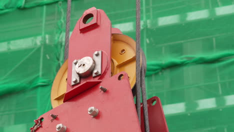 hook block of a tower crane working with scaffoldings in background