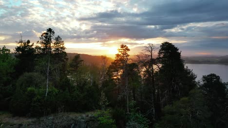 Sunset-falls-behind-the-mountains-and-trees-near-Toensberg,-Norway
