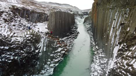 Fly-above-creek-flowing-in-valley-with-rocky-banks