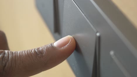 dedo en un interruptor de luz gris oscuro