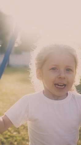 adorable blonde girl plays with butterfly net running in green sunny garden at bright back sunlight closeup