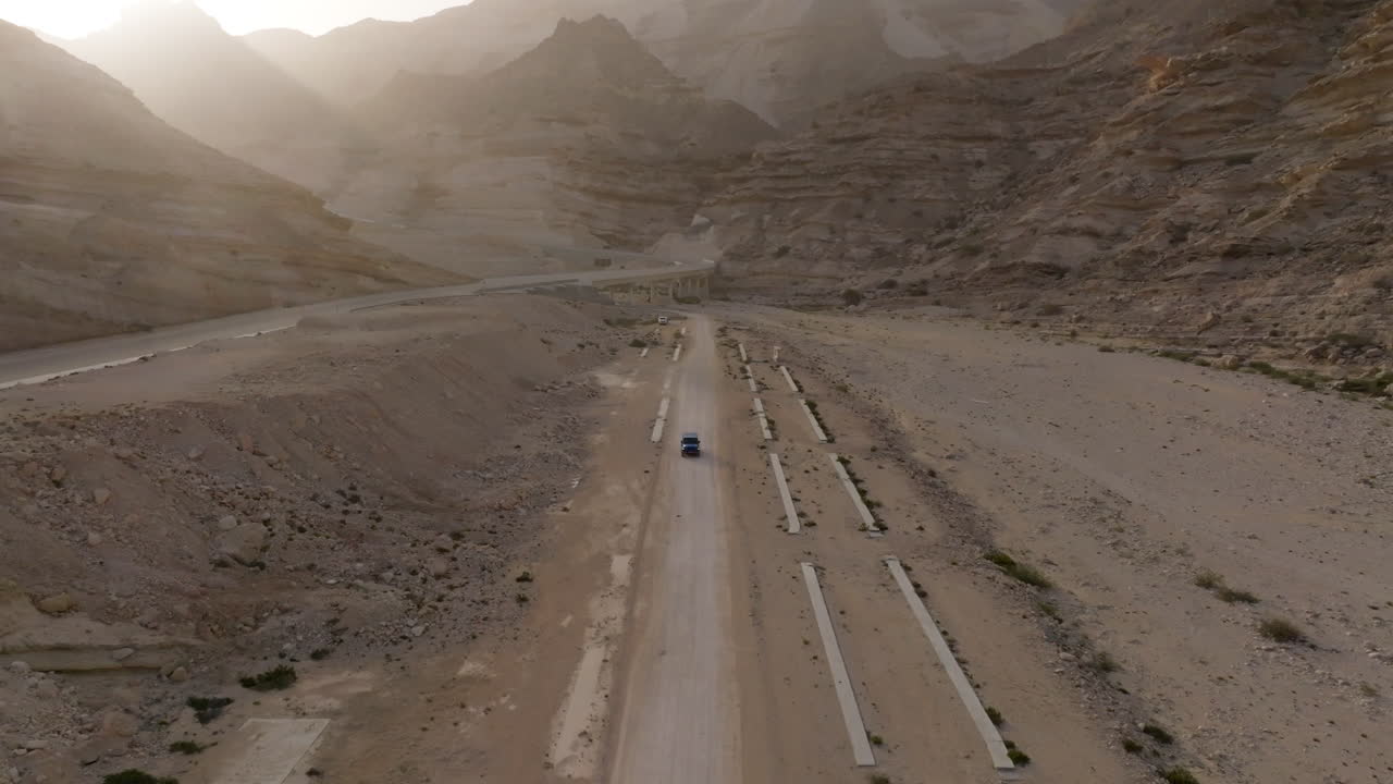 Desert road leading through barren landscape in the oasis of Oman with mountains