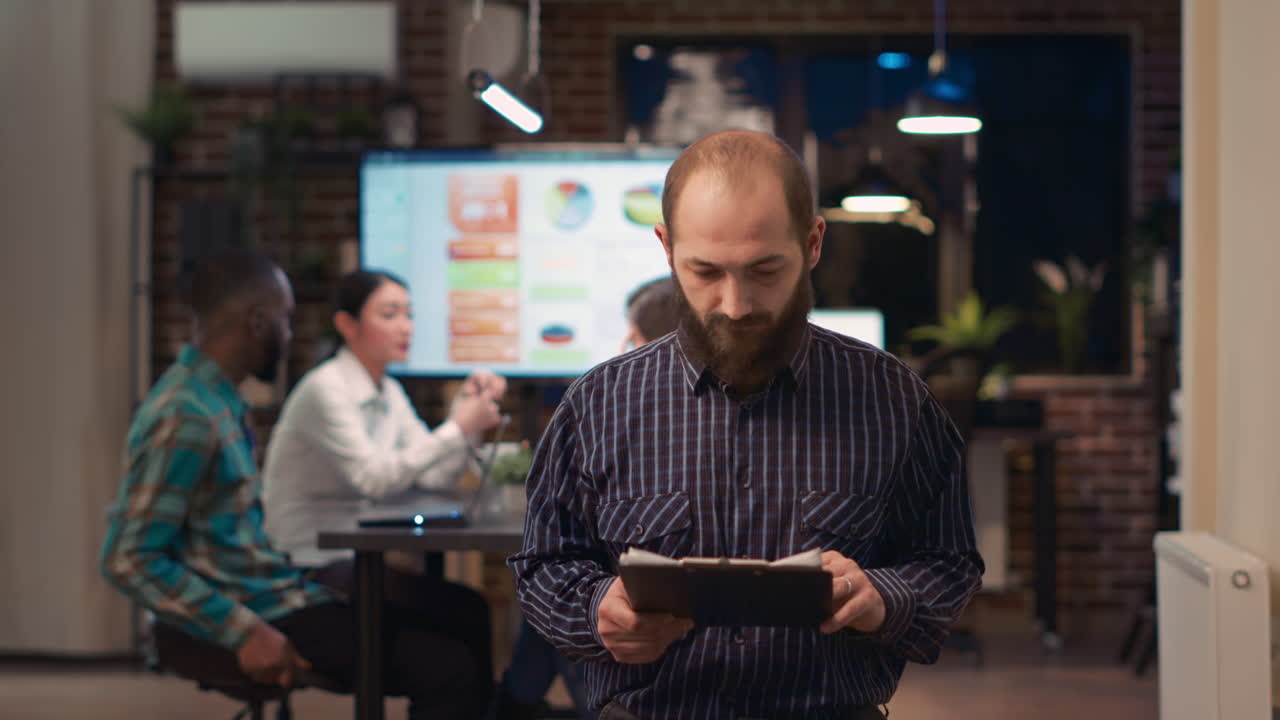 Employee reading report, holding clipboard, looking at camera, smiling