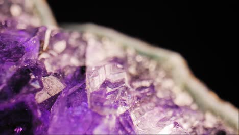 stunning macro cinematic pan of purple amethyst crystal lit against black background