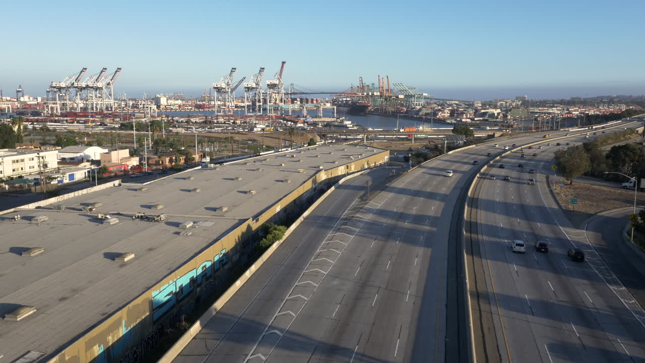 Aerial View of a Busy Freeway Leading Towards a Large Shipping Port with Cranes