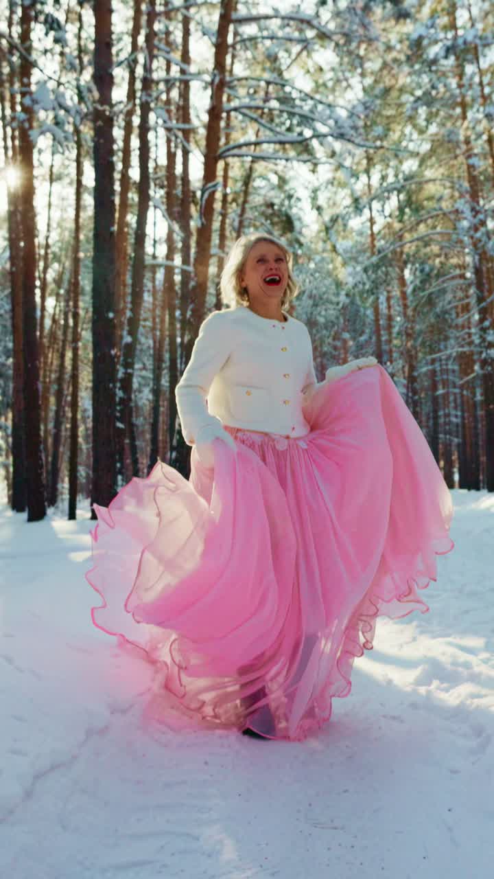 Donna gioiosa che ride con un vestito rosa in una foresta invernale innevata.