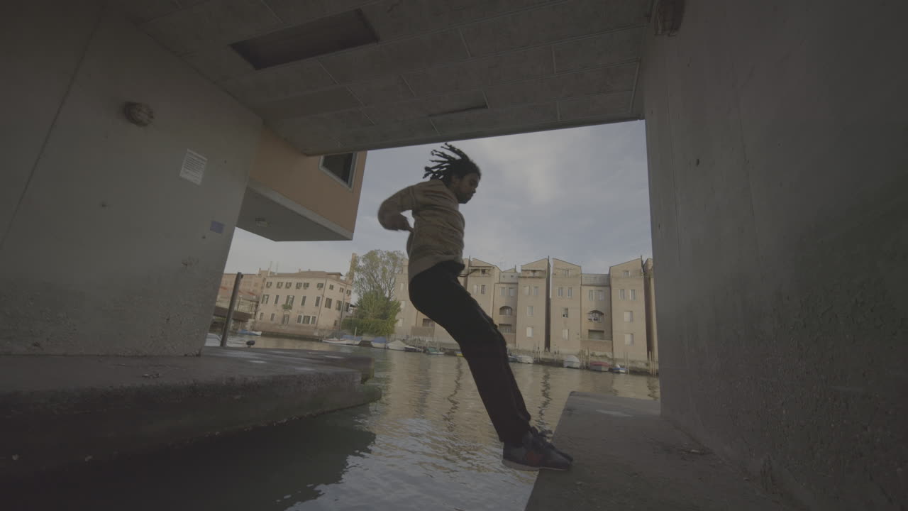 Man Jumping Over Canal in Urban Setting