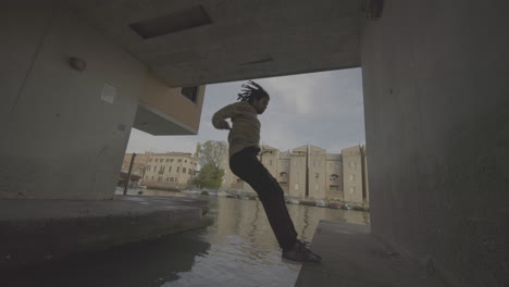 man jumping over canal in urban setting