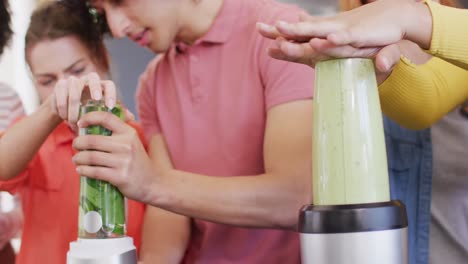 happy group of diverse friends preparing healthy drink in kitchen together