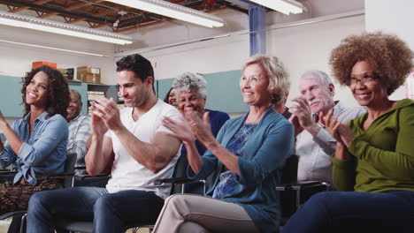 group attending neighborhood meeting in community center clapping