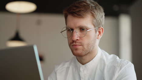 male student with glasses is reading info on laptop display learning online technology for distant education