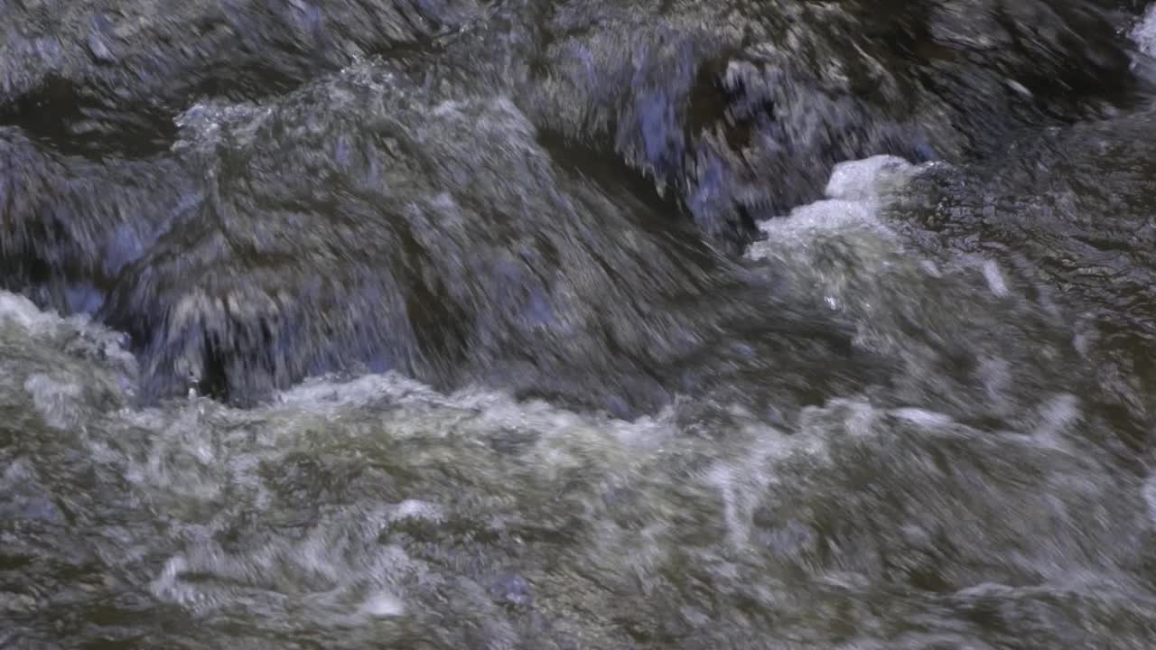 Primo piano di un ruscello d'acqua torbida che scorre sulle rocce