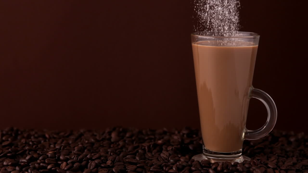 Zucchero che si versa in un bicchiere di caffè