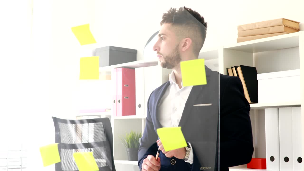 hombre de negocios con pluma en la mano pensando cerca de la pared de vidrio