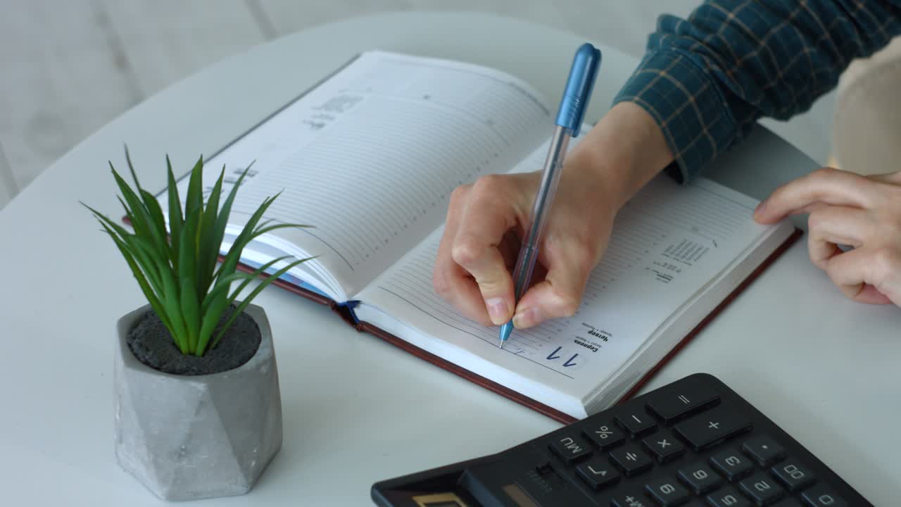 manos de la mujer escribiendo notas y usando calculadora