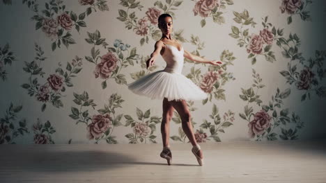 ballerina in white tutu on pointe against floral wallpaper