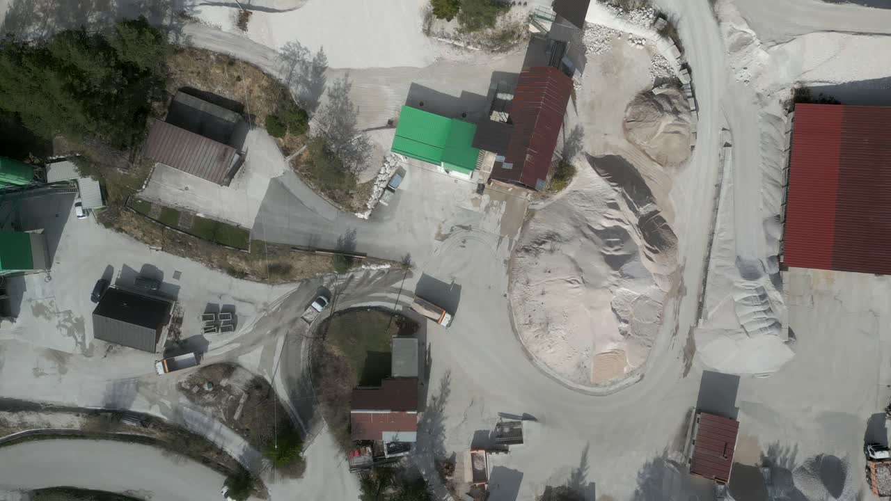 Spiraling aerial movement above the mining site with moving vehicles for construction industry.