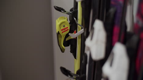 a person placing a pair of alpine skis in a rack besides other skis