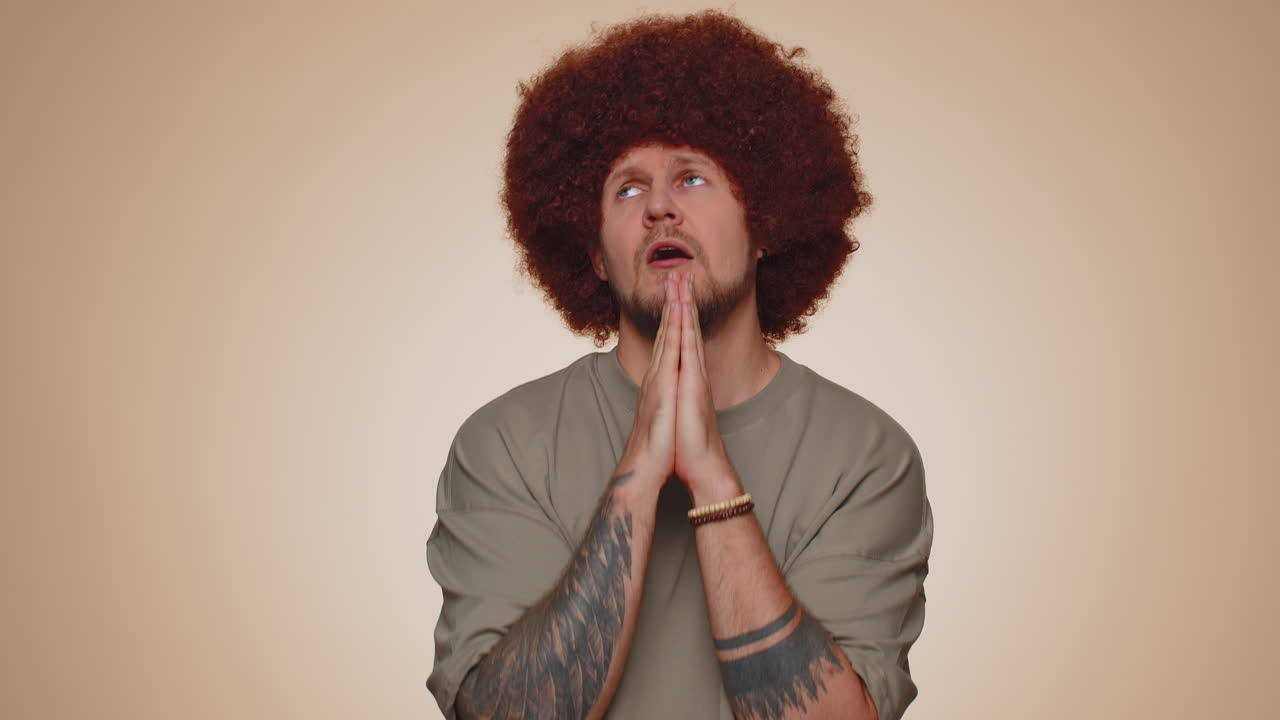 joven adulto de moda orando, mirando hacia arriba y haciendo un deseo, pidiendo ayuda a dios, pidiendo disculpas