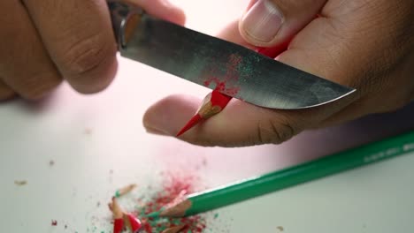 Footage-of-hands-slowly-sharpening-a-pencil-and-some-coloured-pencils-with-a-sharp-knife