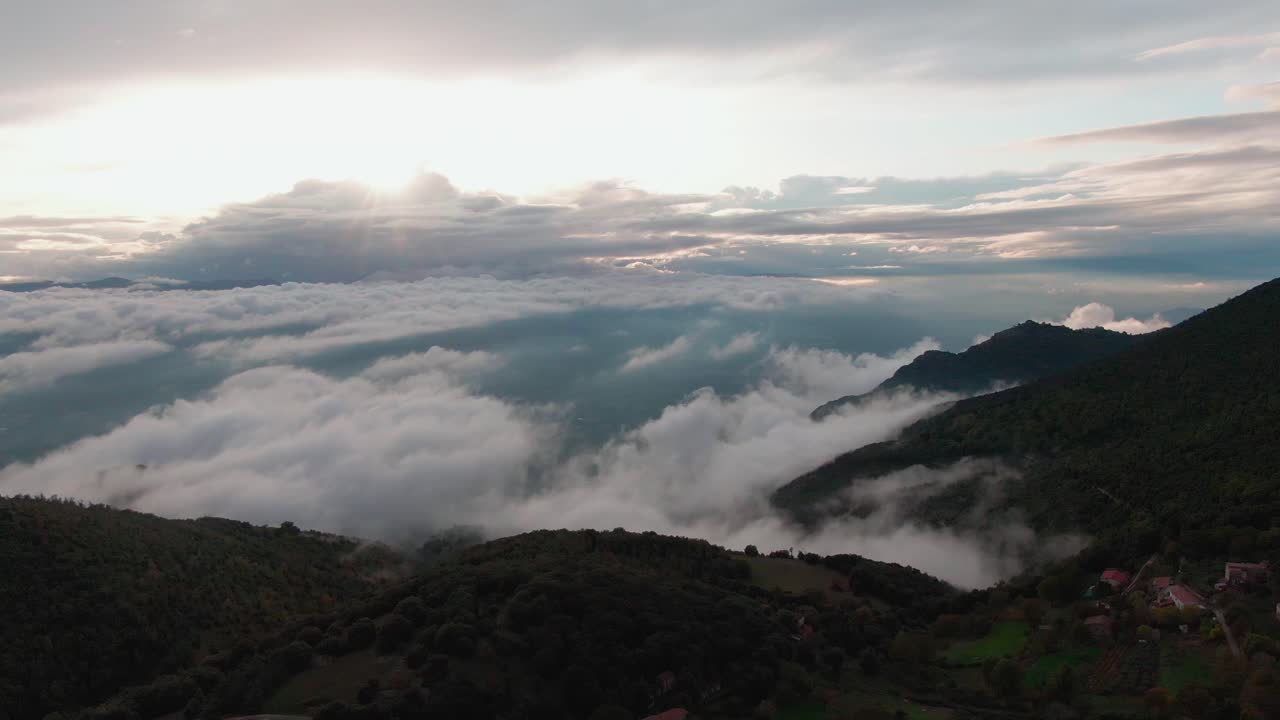 산꼭대기에 있는 작은 산 마을 위의 후진 비행, 계곡의 밝은 흰색 태양과 일몰 시 푸른 하늘의 광선의 아름다운 전망, 공중 철수