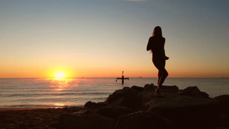 Acrobatic-sexy-woman-practicing-dancing-yoga-on-the-beach-at-sunrise