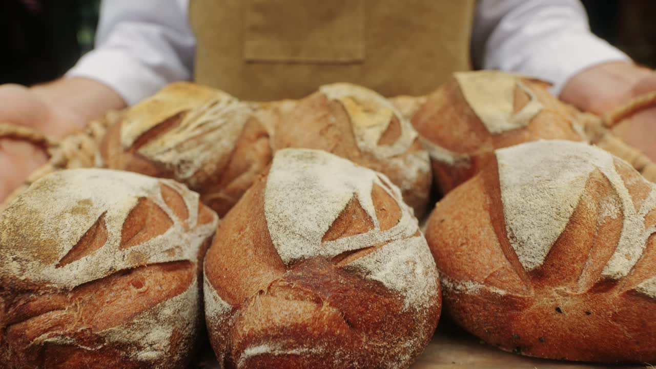 The baker holds in hands a of fresh bread close-up. Artisan bread is making by skill bakers using natural and high-quality ingredients. Food with health and flavour benefits.
