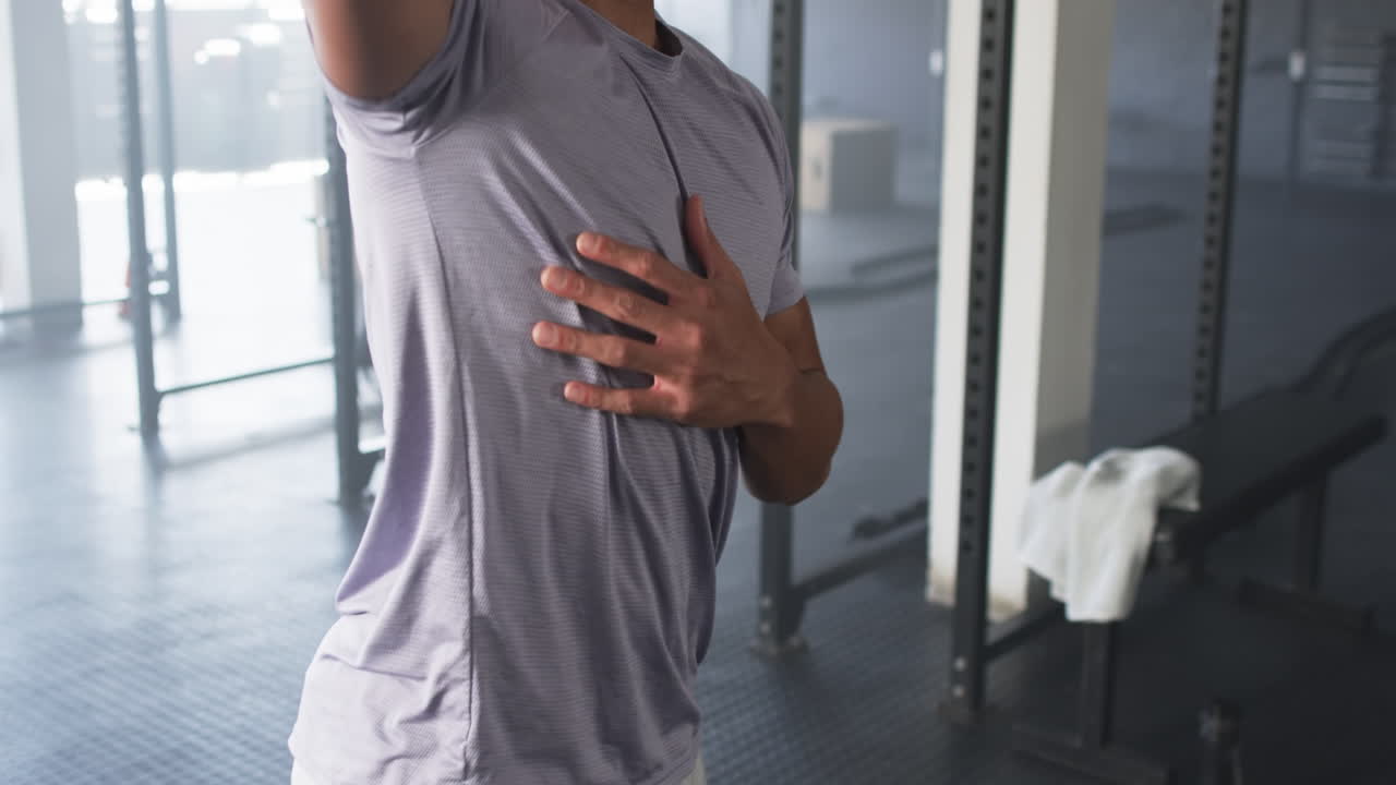 Giovane uomo con i capelli ricci che si allena in palestra, indossando una maglietta viola chiaro