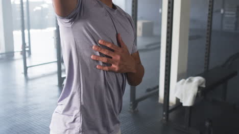 young man with curly hair working out in gym, wearing light purple shirt